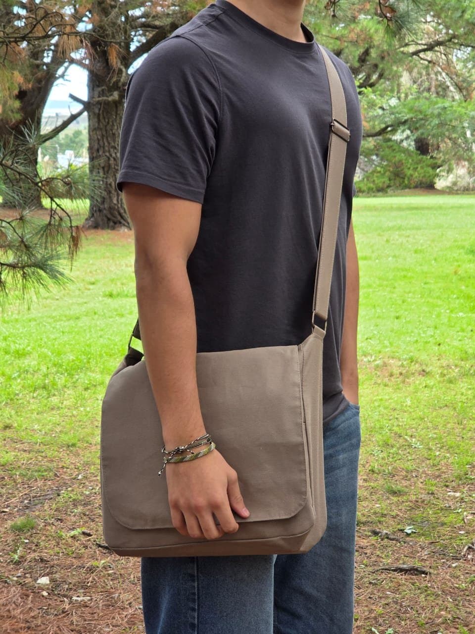 Morral Beige V1 colgado al hombro, de costado, en un parque