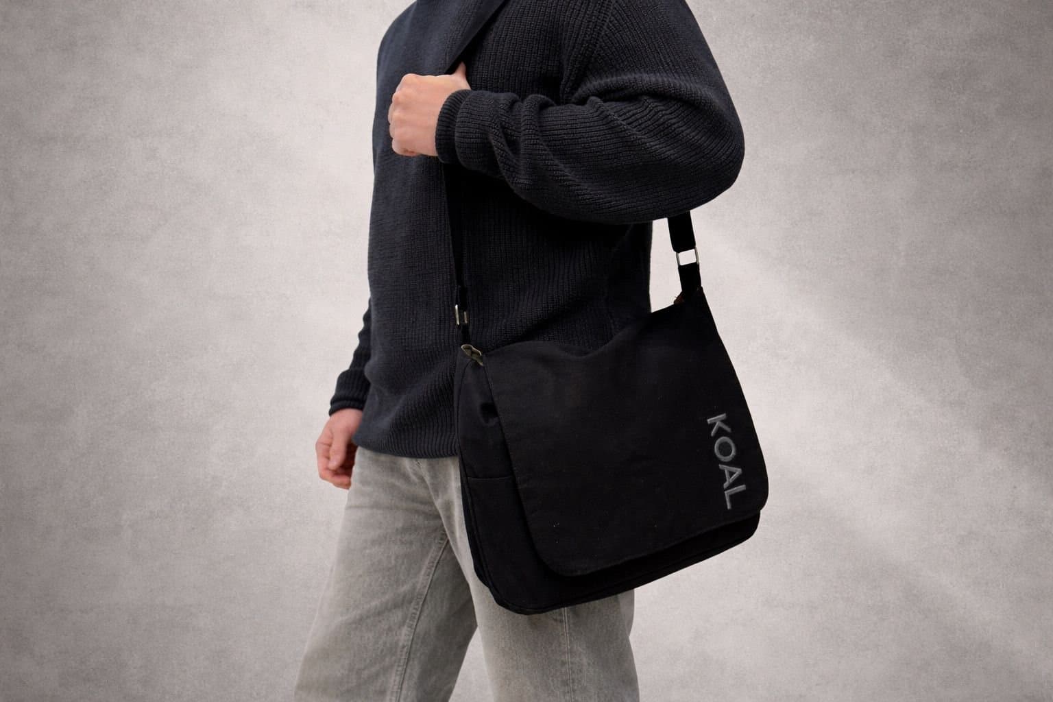 Morral Negro V1 al hombro, de costado, sobre fondo gris