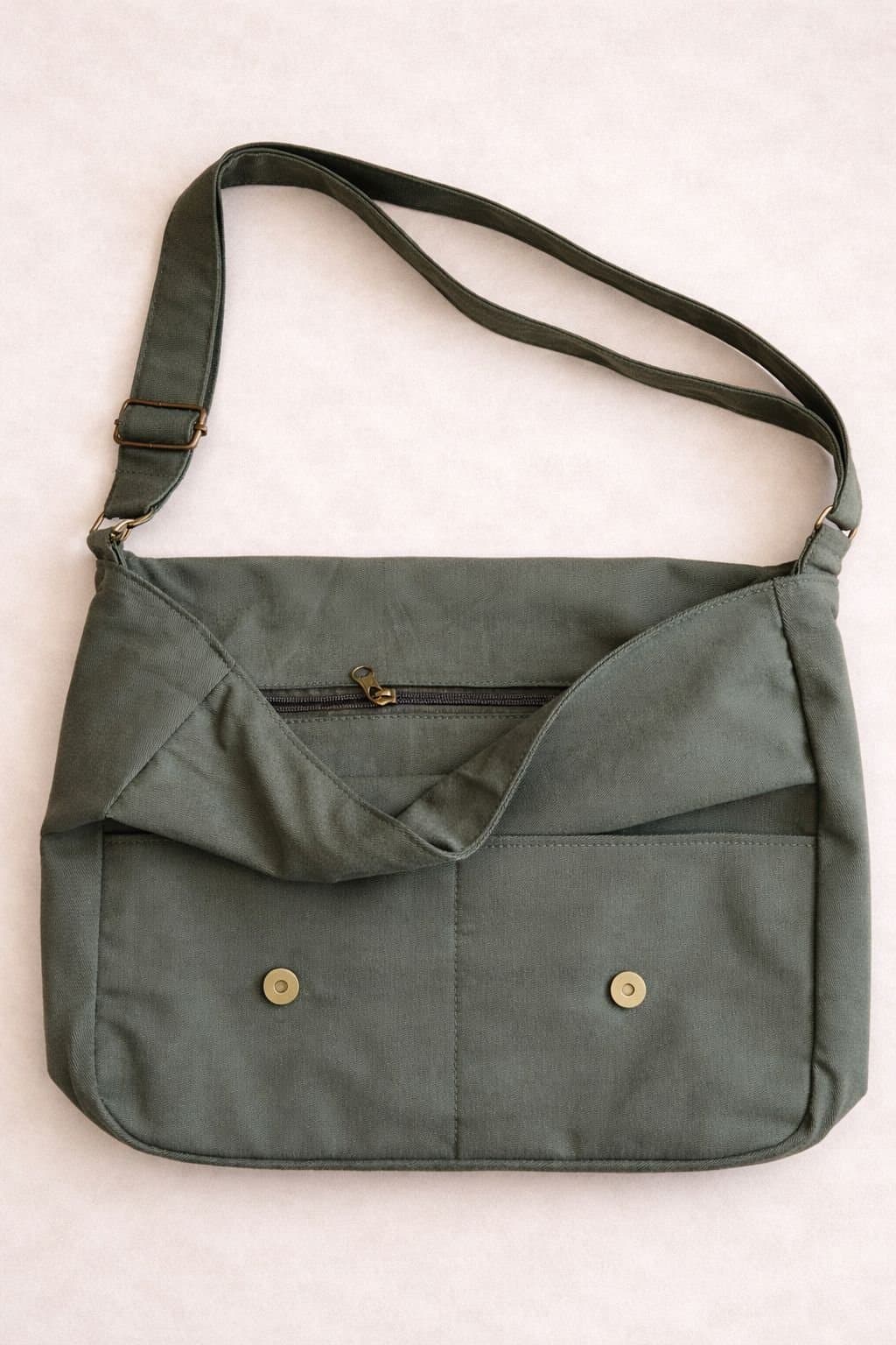 Detalle de un morral KOAL verde: la trama de la gabardina, los bolsillos frontales y los botones de bronce